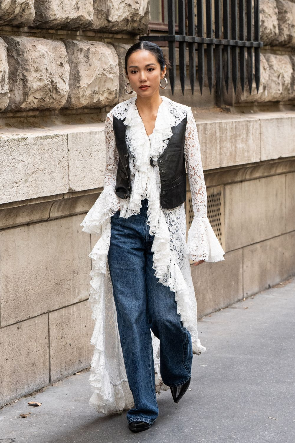 Elegancka damska tunika w stylu boho zestawiona ze spodniami jeansami damskimi, prezentowana na ulicy.