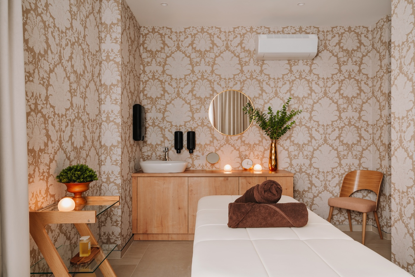 Eleganckie spa i pokój do masażu w Forest Park Resort & Spa z białym stołem do masażu, roślinami i dekoracyjną tapetą na ścianie.