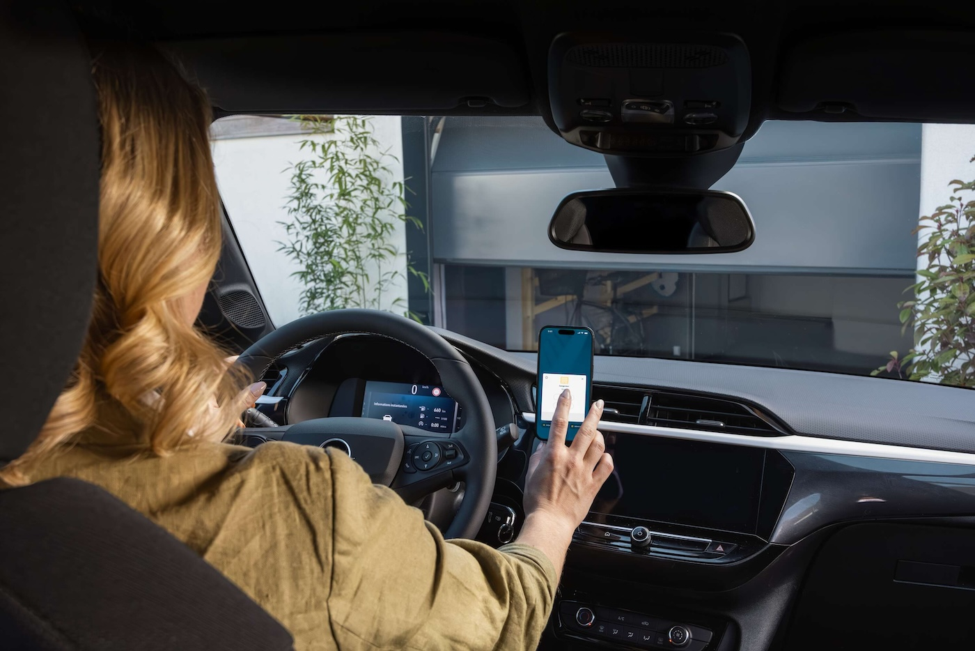Kobieta w samochodzie używająca aplikacji na smartfonie.