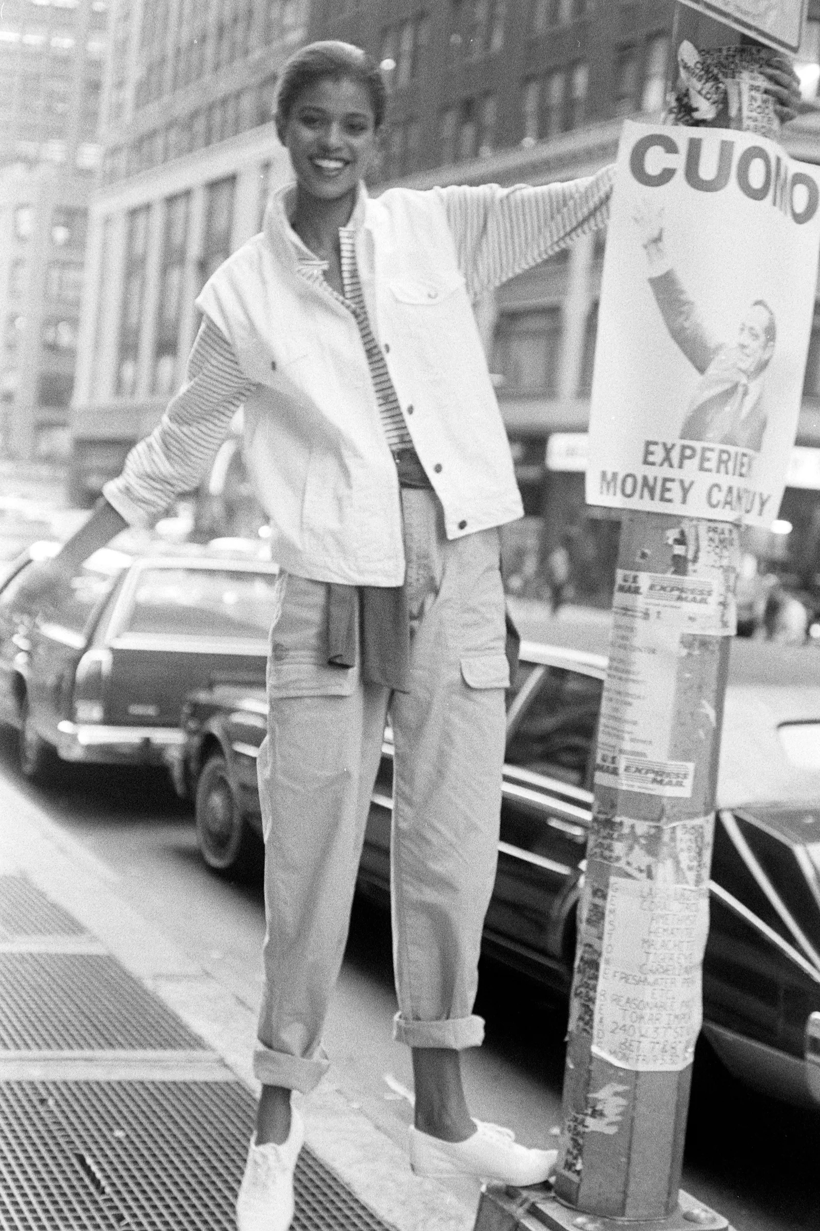 Kobieta w jeansach cropped z podwiniętą nogawką, nosi białą kurtkę i sportowe buty, lata 80.