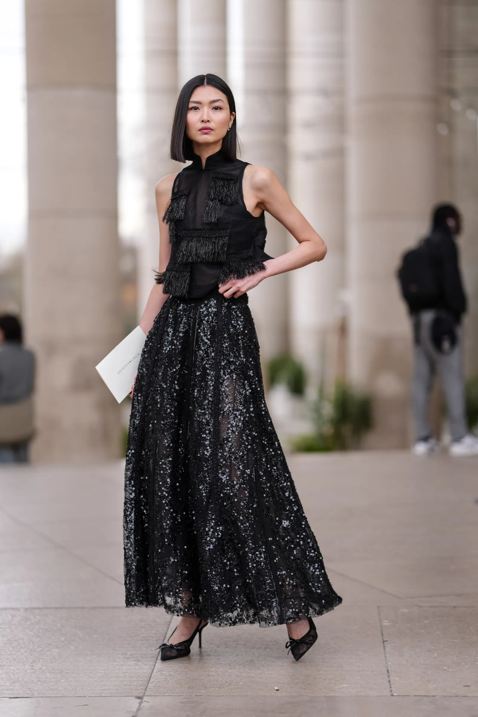 Elegancka bluzka z frędzlami i długa spódnica cekinowa tworzą wyjątkowy, stylowy look.