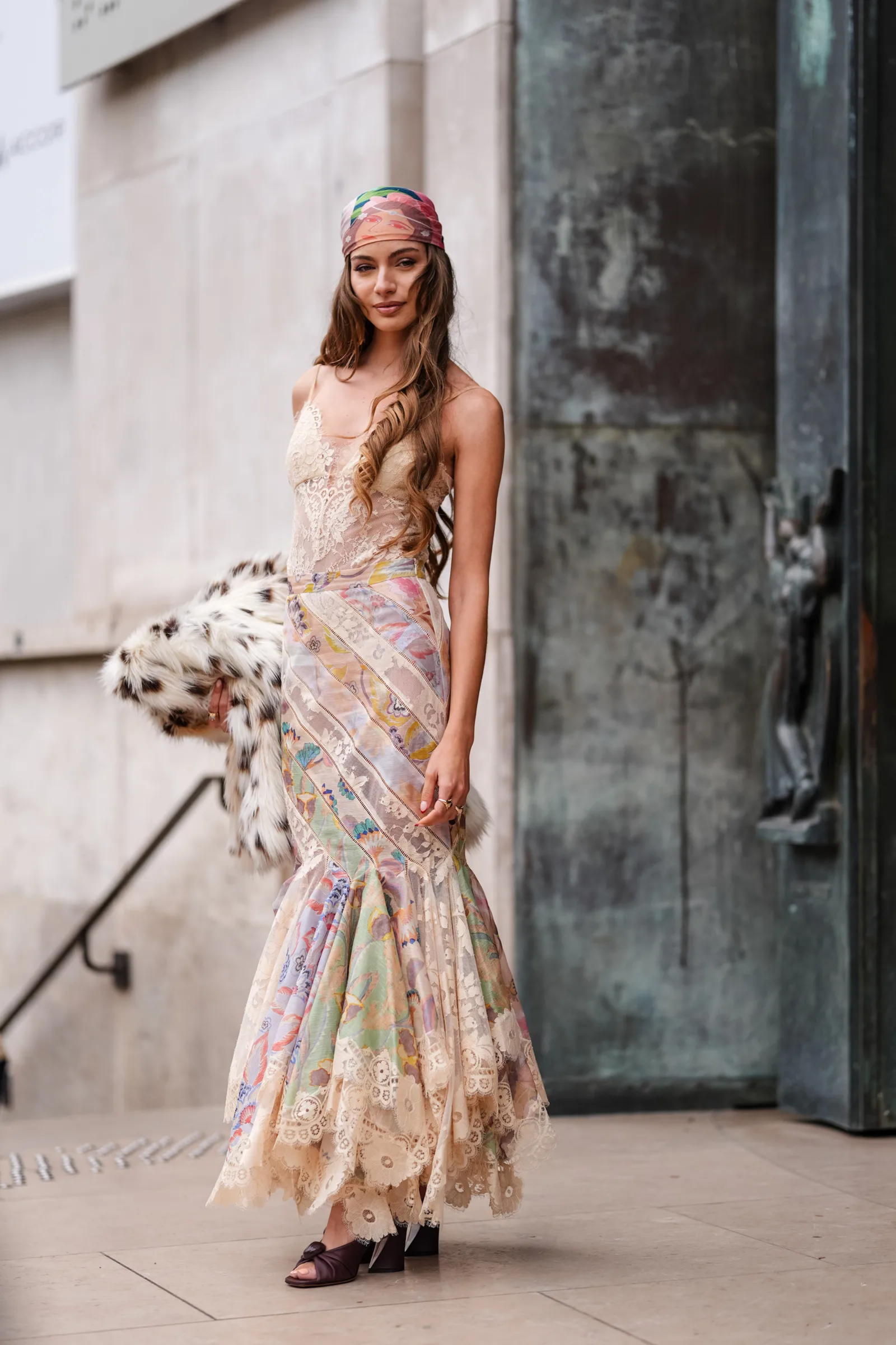 Stylowa modelka w długiej spódnicy w stylu boho i bieliźnianej bluzce, trzyma futrzany element odzieży.