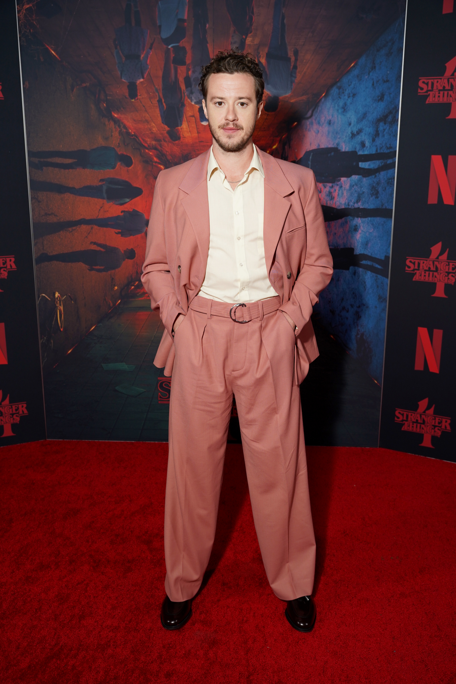 Aktor Joseph Quinn na premierze czwartego sezonu serialu Netflix "Stranger Things", ubrany w różowy garnitur.