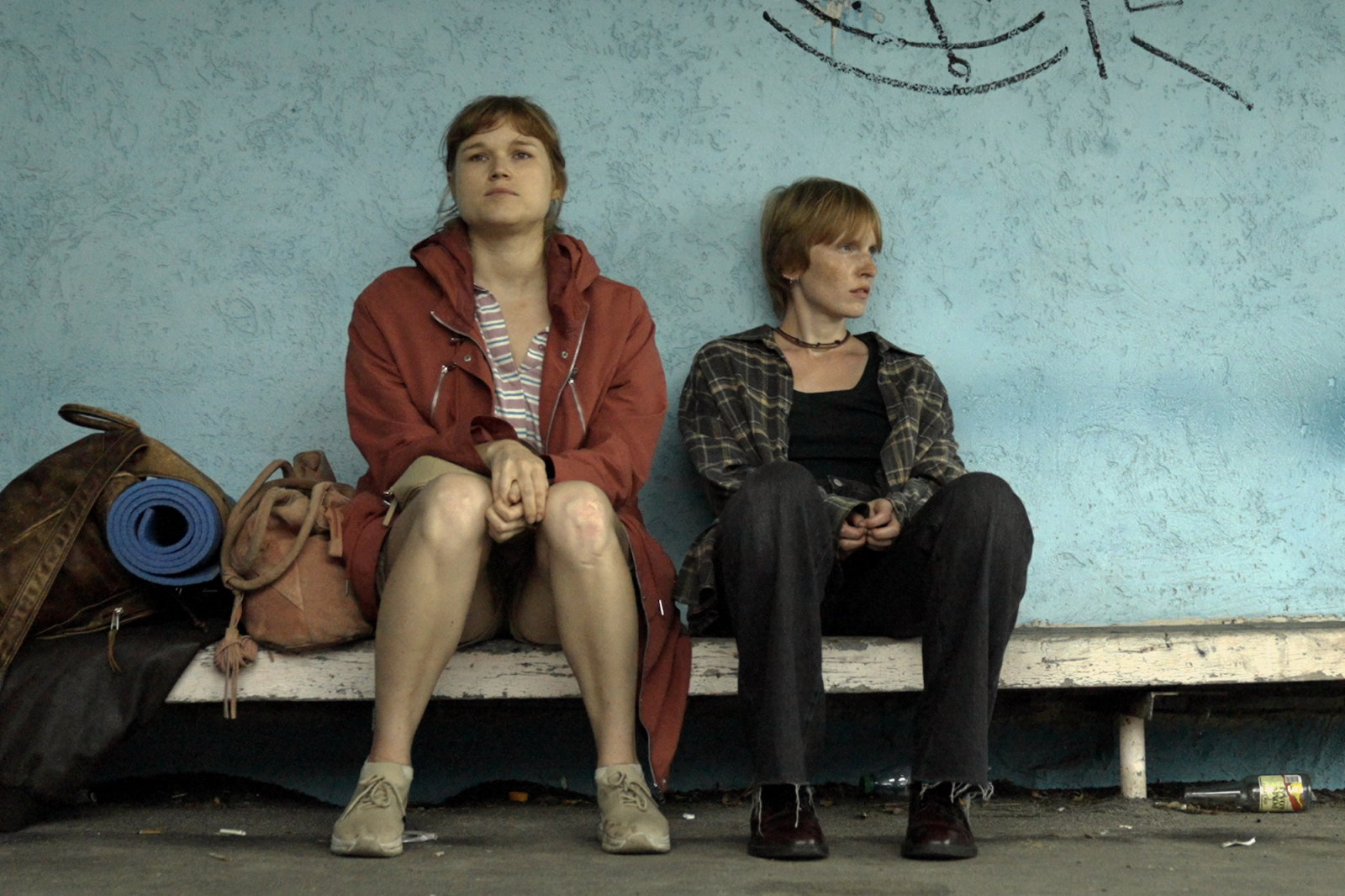 Diana Zamojska i Karolina Rzepa w polskim filmie „Dwie siostry”, siedzą na ławce w miejskim otoczeniu.