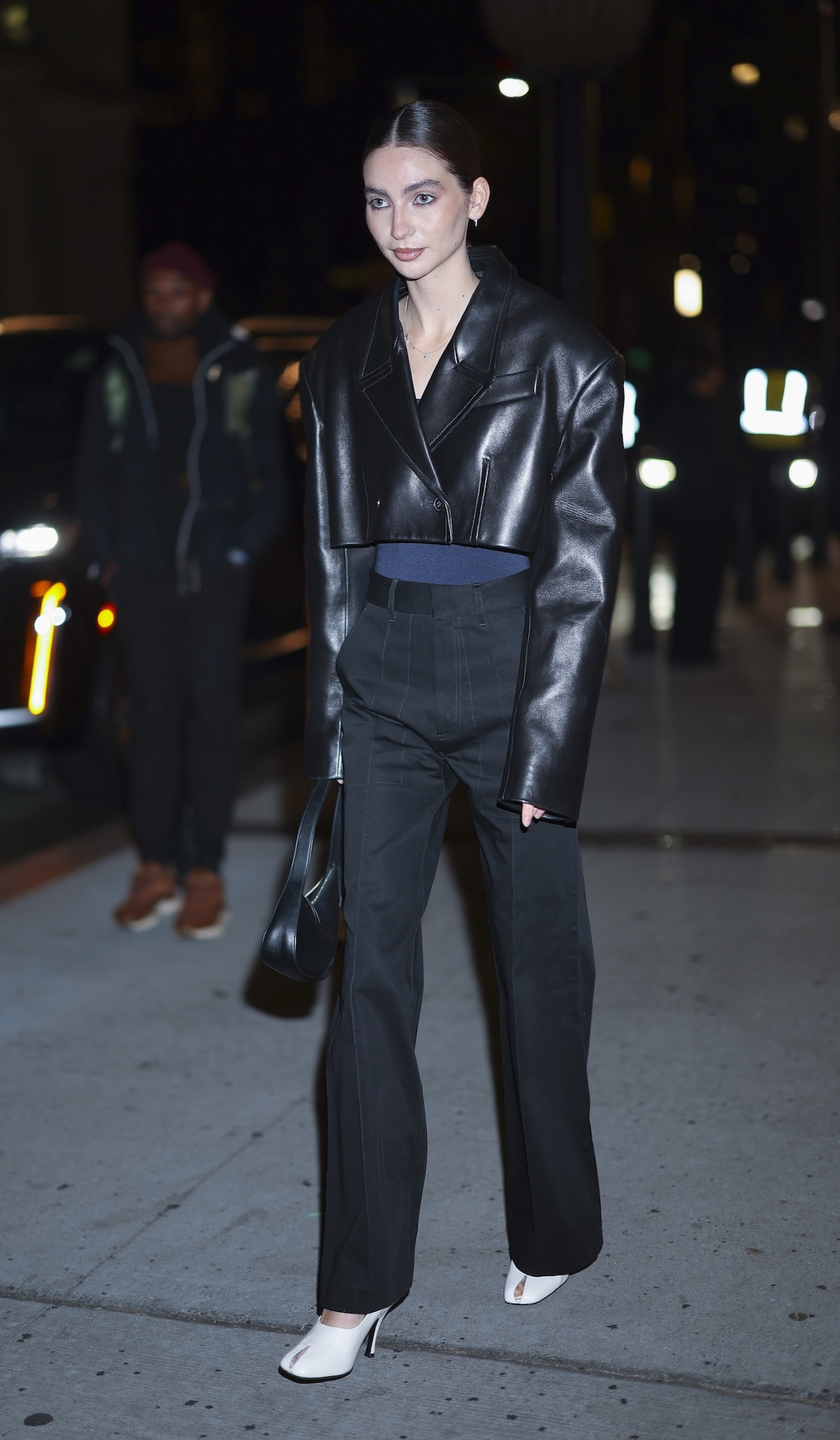 Meadow Walker ma na sobie białe buty peep-toe marki Khaite (modę Eva), granatowy top, krótką czarną skórzaną kurtką i eleganckie czarne spodnie.