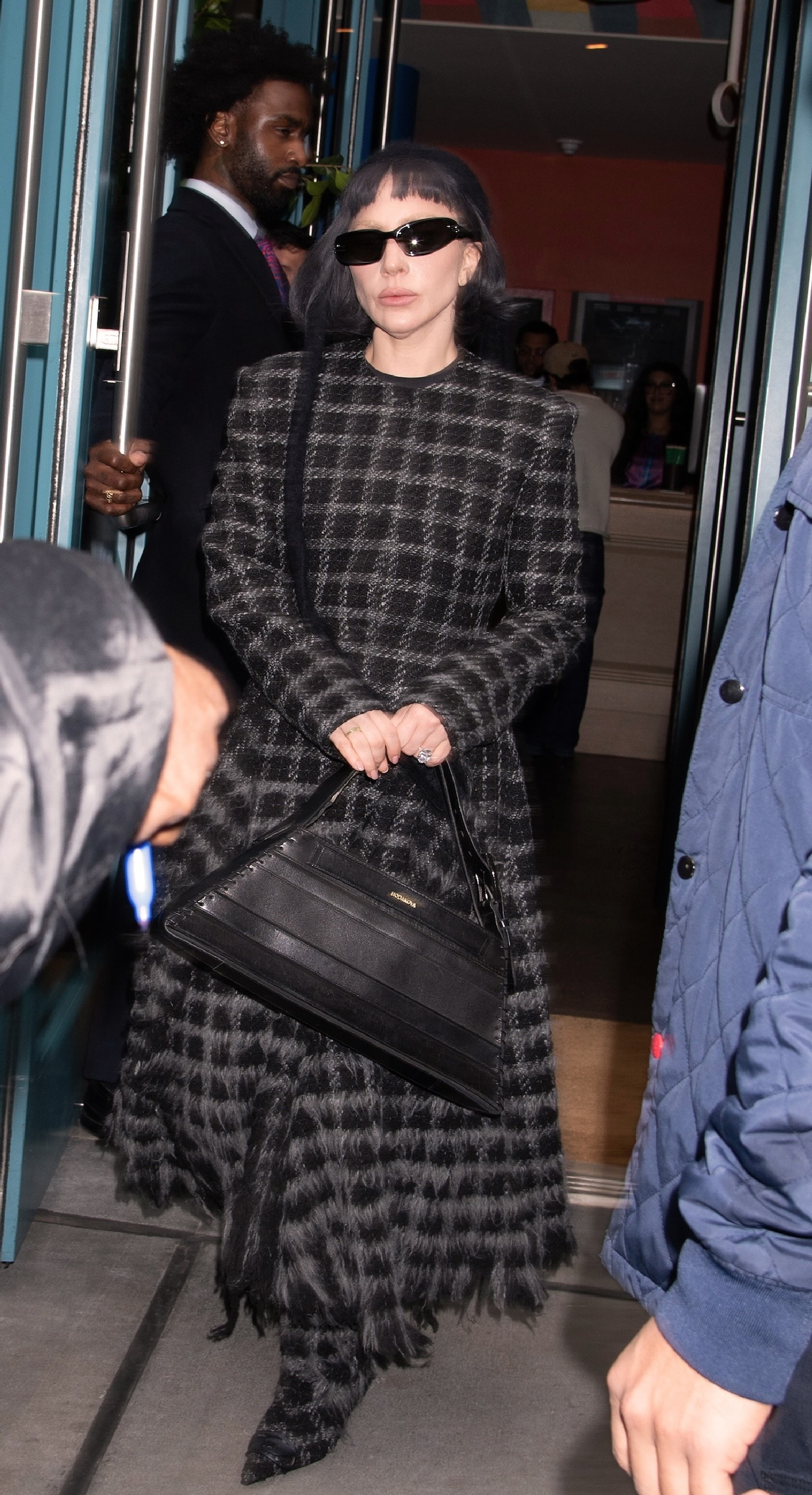 Lady Gaga na ulicy Nowego Jorku w kraciastym komplecie marki Diesel na sezon jesień-zima 2025-2026, kozakach z obcasem kitten heels, czarnych okularach przeciwsłonecznych i torebką marki Diesel.