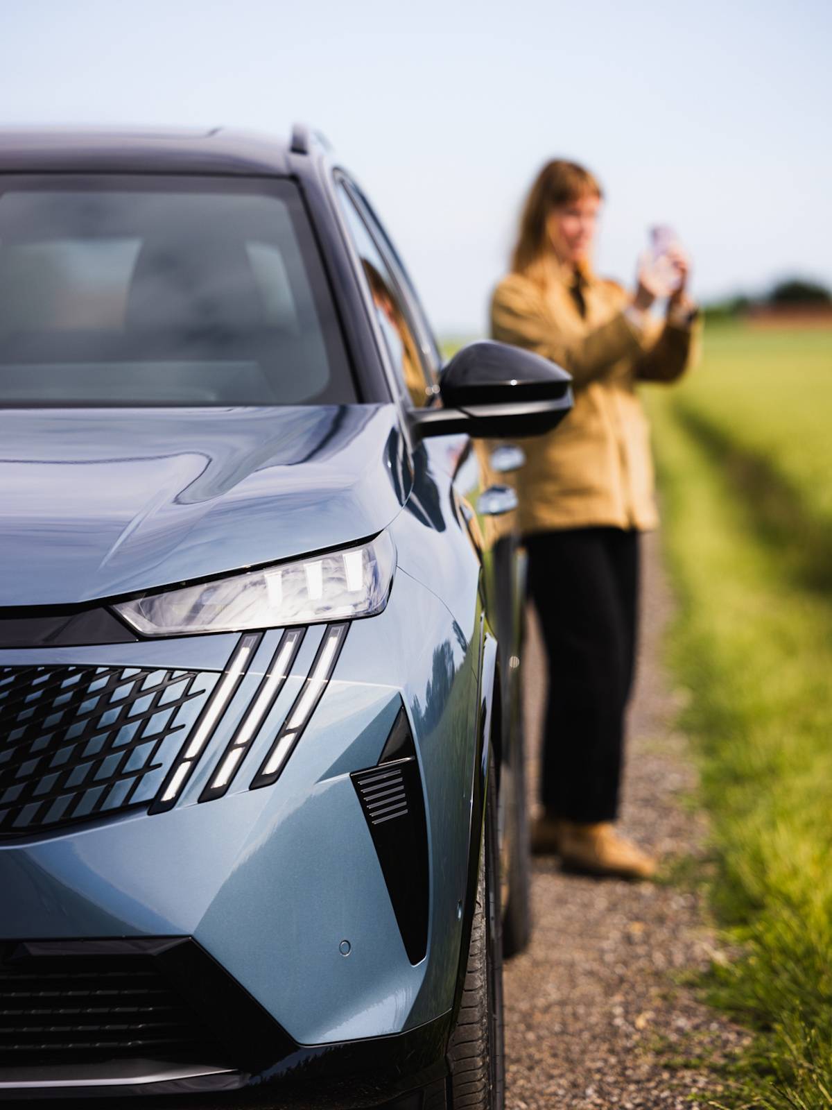 Kobieta robiąca zdjęcie obok samochodu Peugeot E-5008