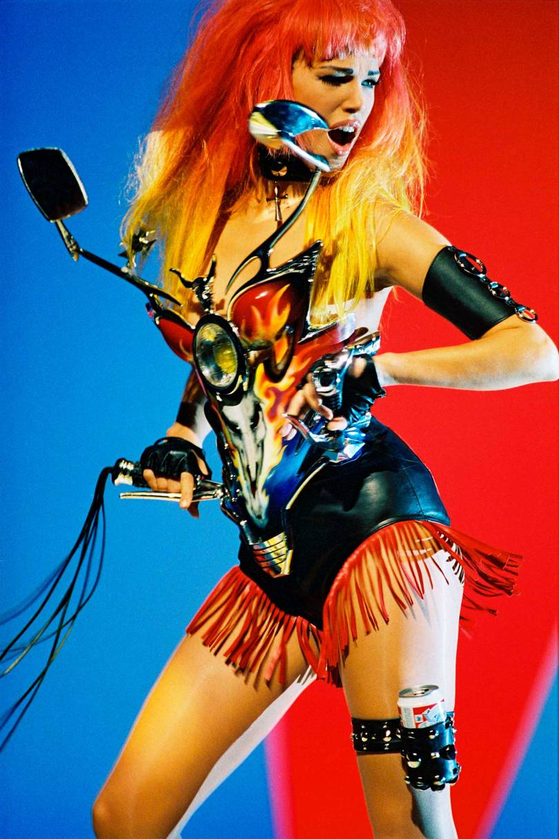 Motorcycle inspiration: A Thierry Mugler Harley Davidson bustier in painted plexiglas (by Jean-Jacques Urcun) with wing mirror detail, worn with fringed leather shorts, and a matching Budweiser garter from the Cowboys collection, Ready-to-Wear Spring/Summer 1992
(© PATRICE STABLE / THIERRY MUGLER)
 