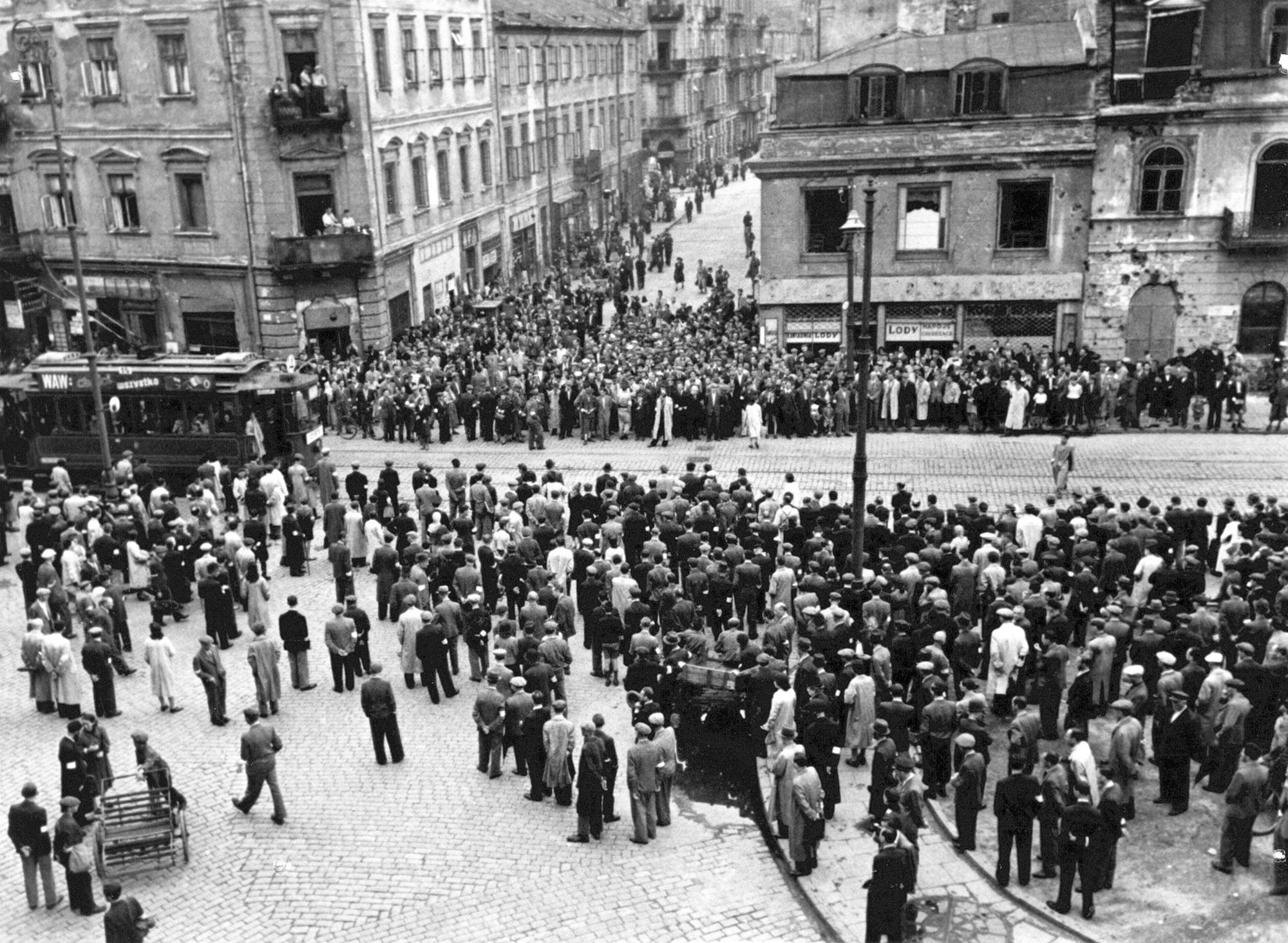 Fotografia z okresu okupacji niemieckiej. Warszawa, getto. Tłum zgromadzony wzdłuż ul. Nalewki przy wylocie ul. Świętojerskiej, przepuszczający tramwaj linii 14. Ujęcie z drugiego piętra domu przy ul. Nalewki 13 w kierunku północno-wschodnim, ok. 1940, fot. Mieczysław Bil-Bilażewski, Muzeum Powstania Warszawskiego