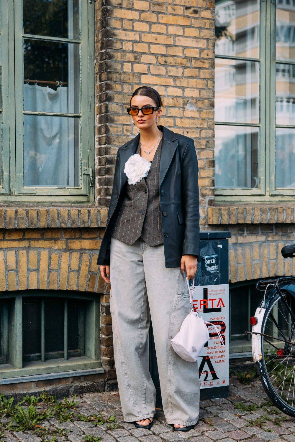 Kopenhaski street style pokazuje, jak szare jeansy zyskują nowe oblicze w zestawieniu ze skórzaną marynarką w stylu retro (Fot. Phil Oh) 